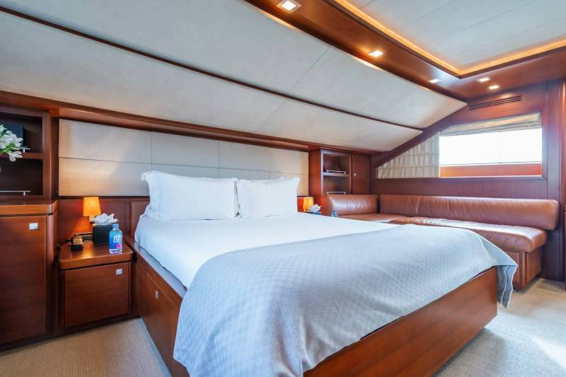 Luxurious yacht stateroom features a plush bed, rich wood accents, and a comfortable leather seating area.