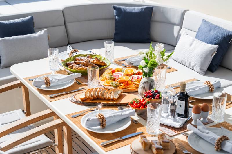 Enjoy a delightful breakfast spread of fresh fruit, pastries, and bread on a sun-drenched yacht deck.