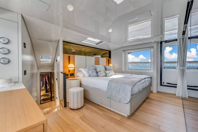 A luxurious yacht bedroom offers stunning ocean views through large windows and a skylight.