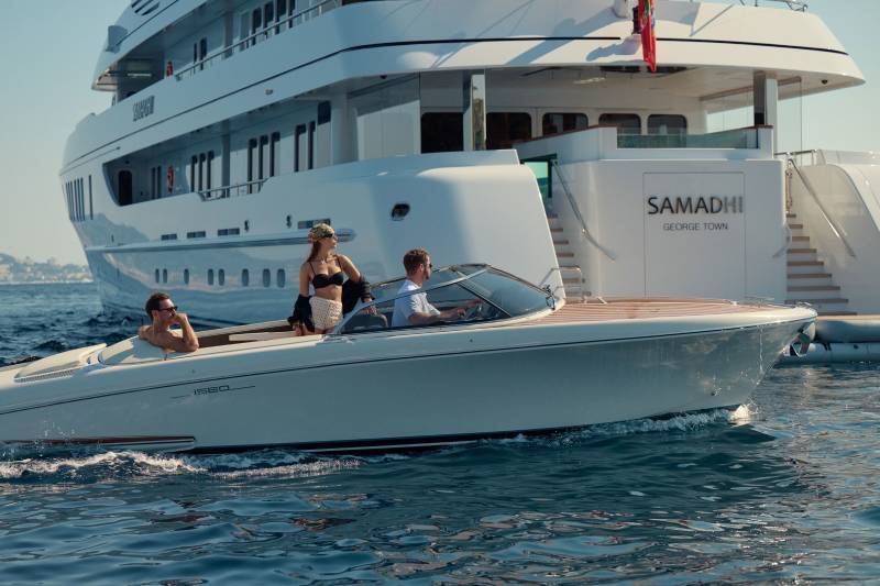 A sleek speedboat carrying three passengers cruises past the luxurious yacht Samadhi docked in George Town.