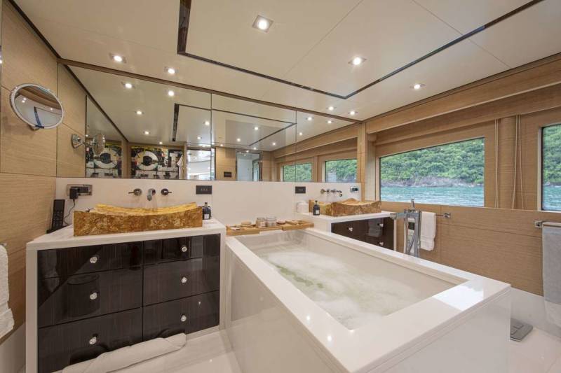 Luxurious yacht bathroom features a deep soaking tub and unique stone vessel sinks with stunning ocean views.