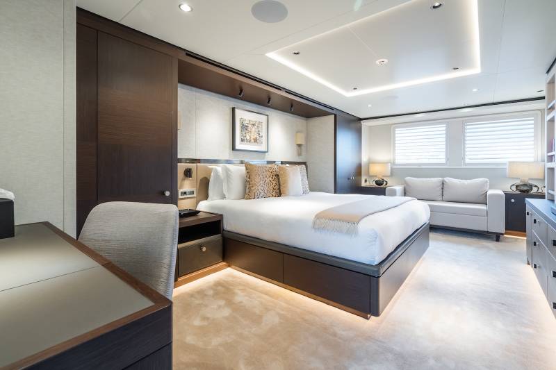 Luxurious yacht accommodations feature a plush king-size bed, elegant cabinetry, and a comfortable seating area with a view.