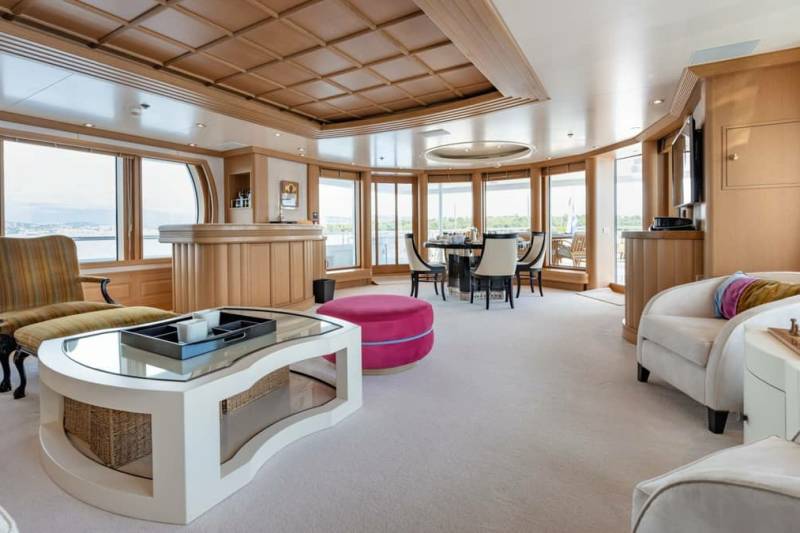 Luxurious yacht interiors offer a refined lounge area with a bar, dining table, and comfortable seating overlooking the water.