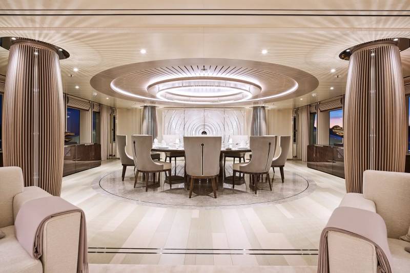 Elegant dining room aboard a luxury yacht features a circular table, plush seating, and sophisticated lighting.