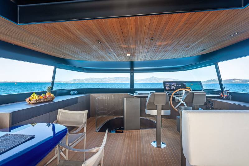 A luxurious yacht's modern interior offers panoramic ocean views from its spacious, wood-paneled deck.
