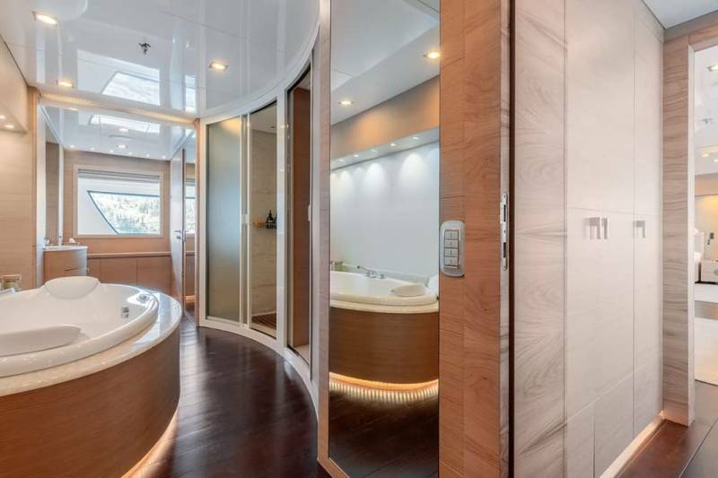Luxurious yacht bathroom features a spacious jacuzzi, sleek shower, and elegant wood and marble finishes.