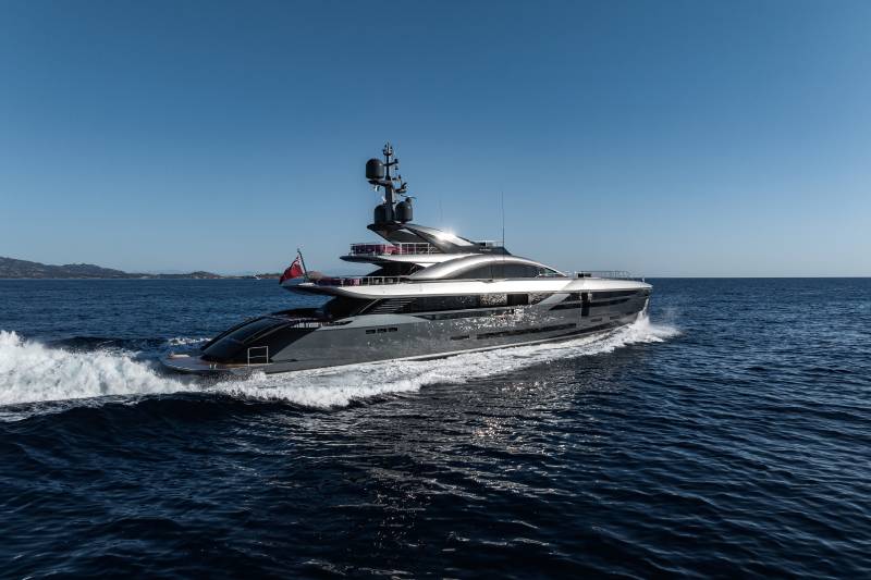 A sleek, multi-level yacht glides through the deep blue ocean under a clear sky.