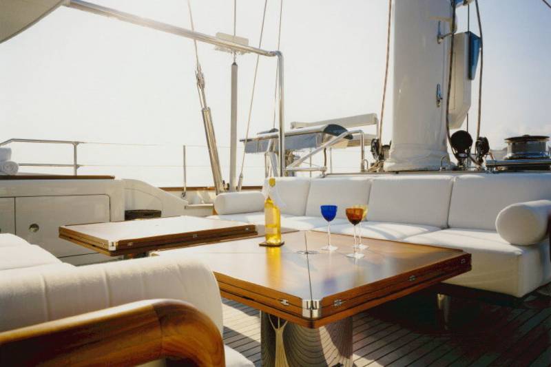 Two wine glasses and a bottle of white wine await guests on a yacht's polished wooden deck.