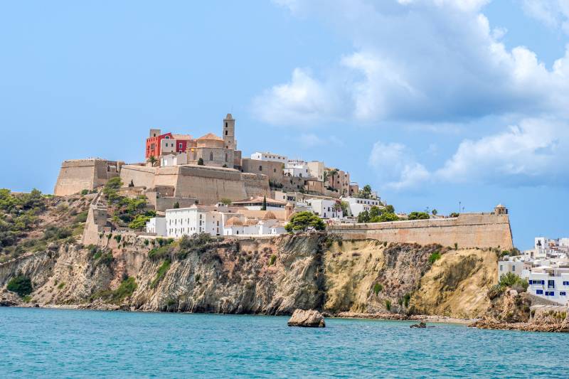 The historic Dalt Vila fortress overlooks the sparkling Mediterranean Sea from its dramatic cliffside perch.