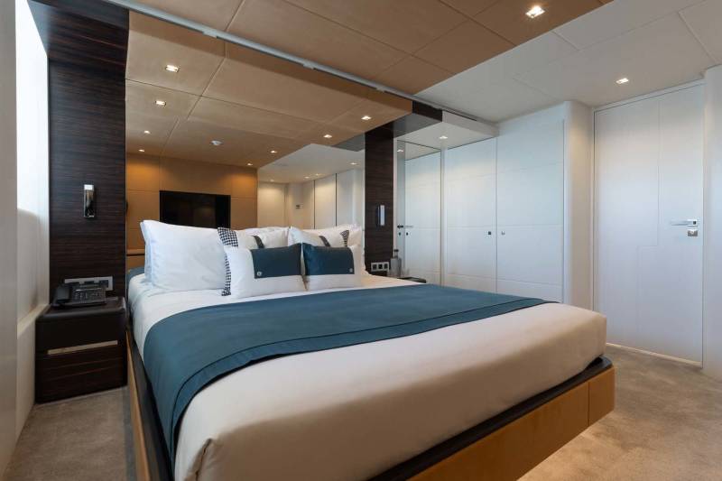 Luxurious yacht cabin features a plush bed adorned with crisp white linens and deep teal accents.