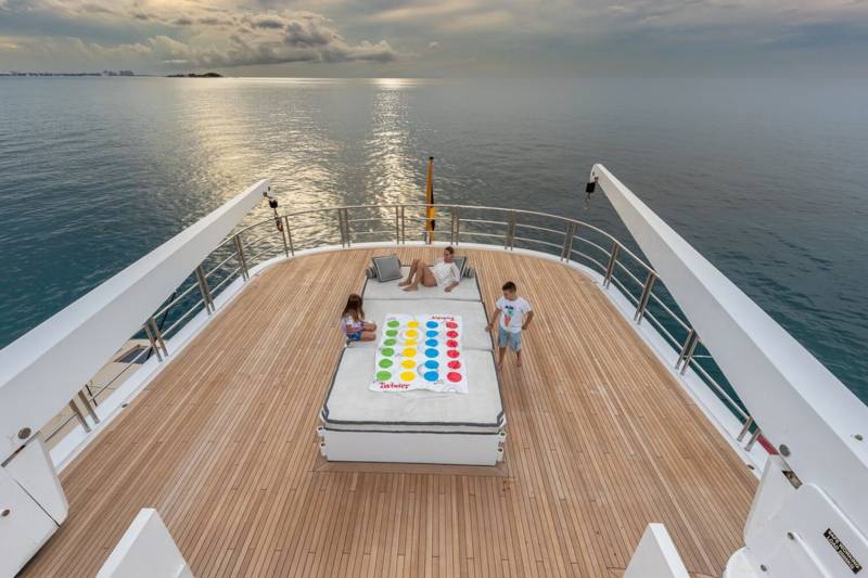 A family enjoys a game of Twister on the deck of a luxury yacht at sea.