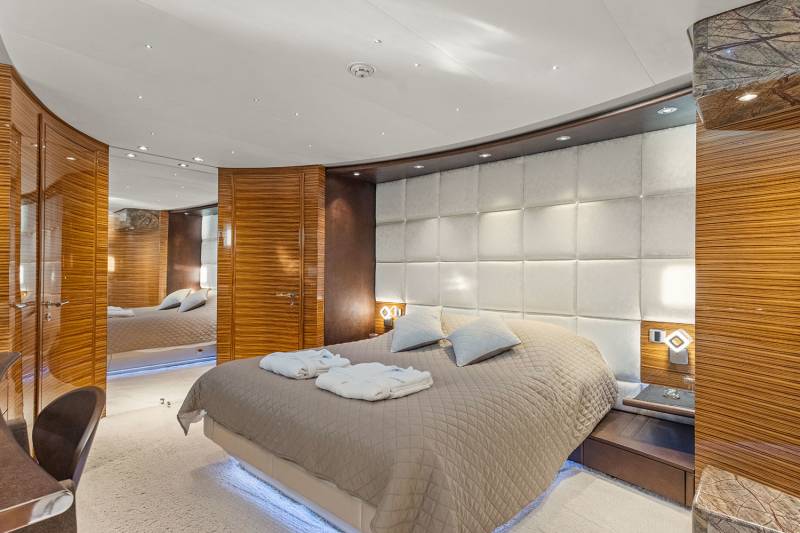 Luxurious yacht bedroom features a tufted headboard, quilted bed, and polished wood accents for an opulent retreat.