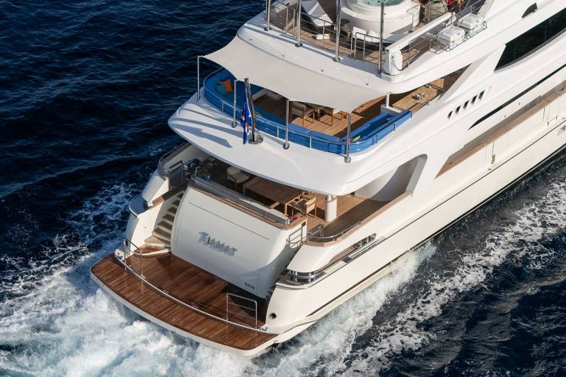 The luxurious superyacht Tiamat glides through the deep blue ocean, leaving a foamy wake behind.