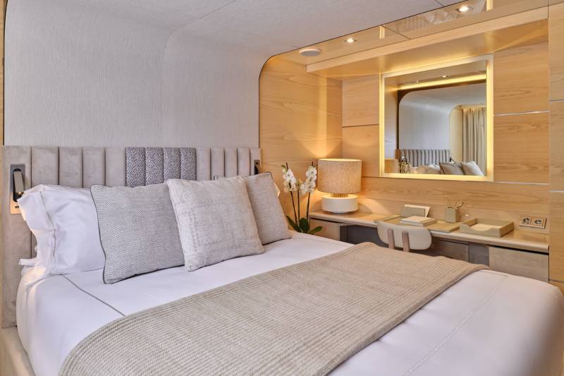 A cozy and well-designed bedroom with a plush bed, a large mirror, and a minimalist decor style, creating a warm and inviting atmosphere.