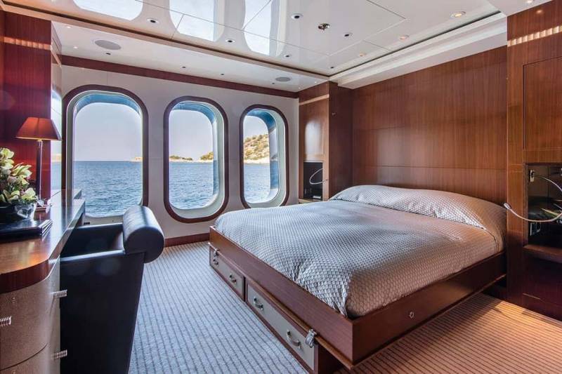 A luxurious yacht cabin offers a serene retreat with ocean views through arched windows and elegant wood paneling.