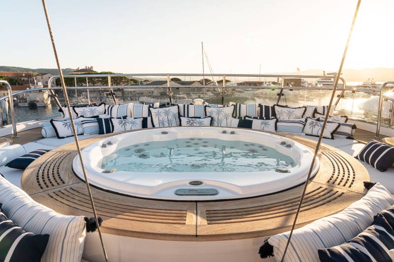 Relax and unwind in the luxurious hot tub on deck, surrounded by plush cushions and a stunning sunset view.
