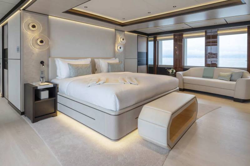 Luxurious yacht stateroom offers a serene retreat with a plush king-size bed, elegant sofa, and stunning ocean views.