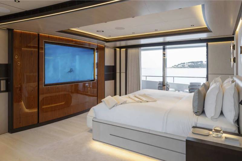 Luxurious yacht bedroom offers a stunning view of the ocean through expansive windows, complemented by a large television screen.