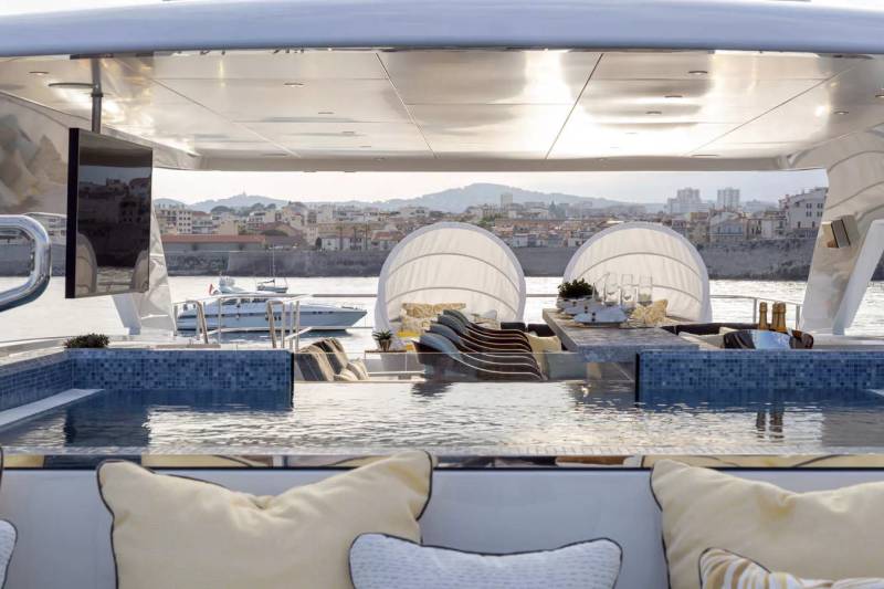 Relax in the infinity pool of this luxurious yacht, with a picturesque coastal town as your backdrop.