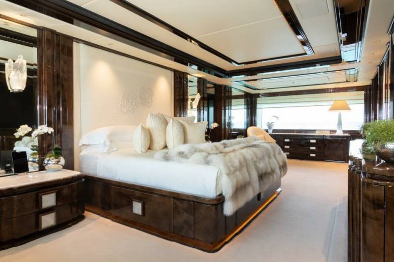 Luxurious yacht bedroom features a plush fur throw, elegant wood finishes, and a serene ambiance with ocean views.