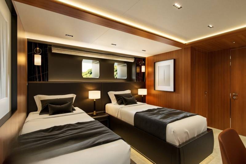 Luxurious twin beds with dark grey linens and modern bedside lamps create a serene atmosphere in this yacht cabin.