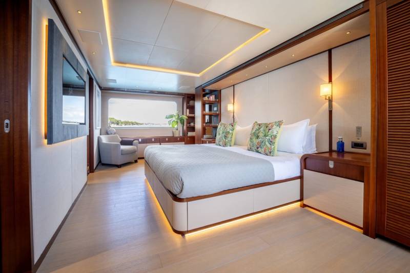 Luxurious yacht cabin features a king-size bed, ambient lighting, and a panoramic window overlooking the sea.