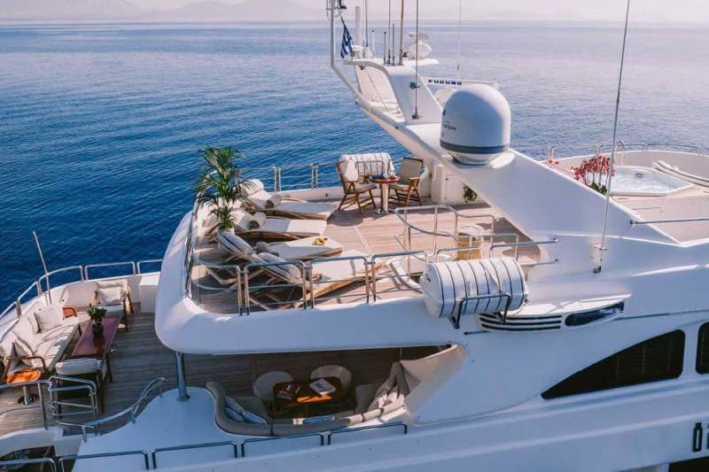Luxurious yacht decks offer ample space for relaxation with comfortable seating, sun loungers, and a soothing hot tub against a backdrop of the serene blue sea.