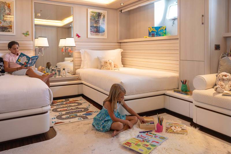 Two children enjoy a cozy cabin on a yacht, surrounded by books, toys, and soft furnishings.