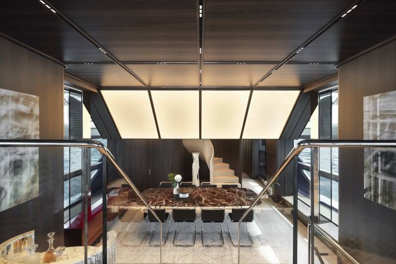 Luxurious yacht interiors feature a marble dining table and spiral staircase overlooking the sea.