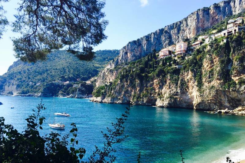 Stunning turquoise waters lap against a dramatic cliffside dotted with charming homes in this idyllic Mediterranean bay.
