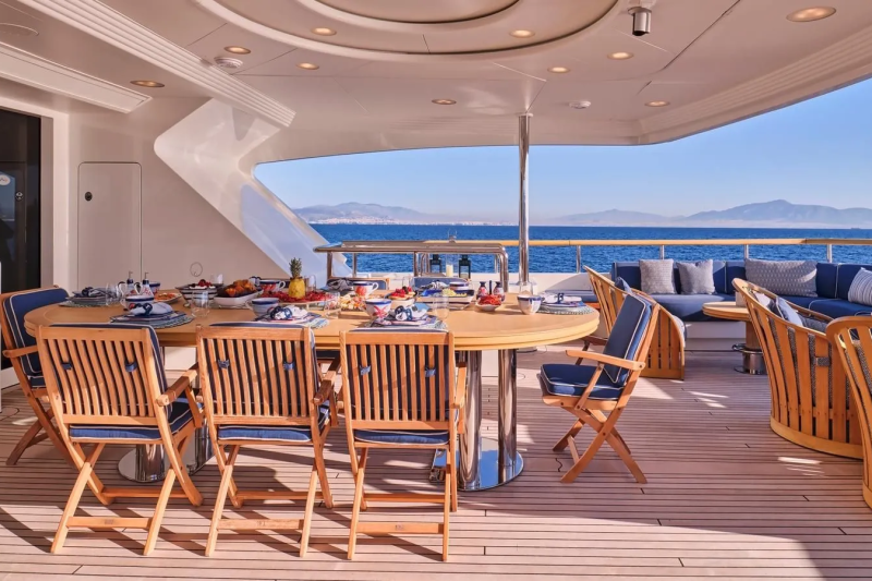 A beautifully set dining table awaits on a yacht's deck, offering a stunning ocean view.
