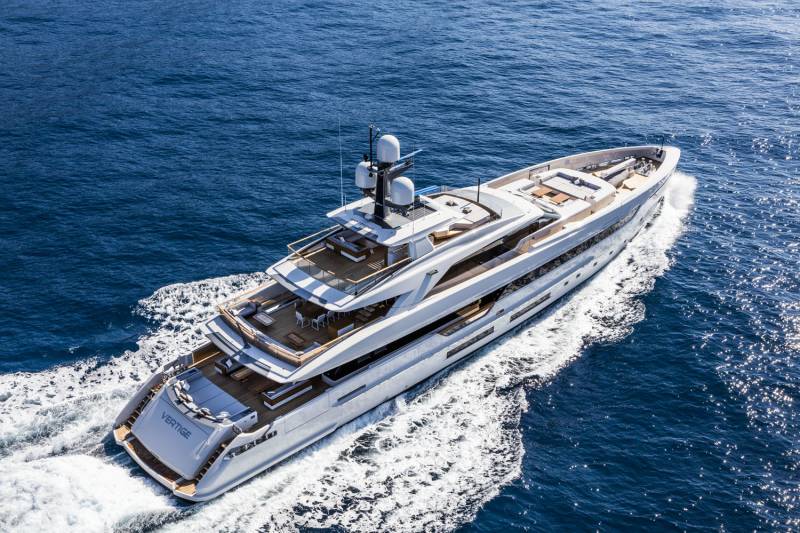 A luxurious white yacht cruises through the deep blue ocean, leaving a white wake behind it.