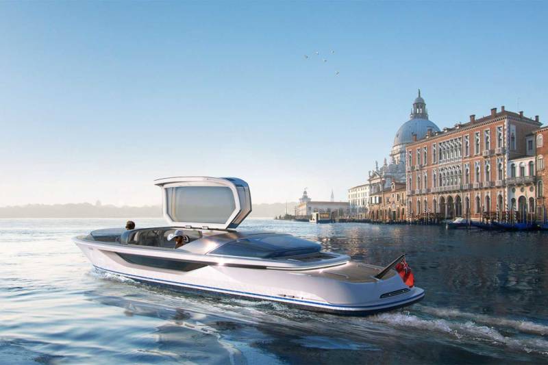 A sleek, modern white motorboat glides through the water in the foreground, with the historic architecture and domed cathedral of Venice lining the background.