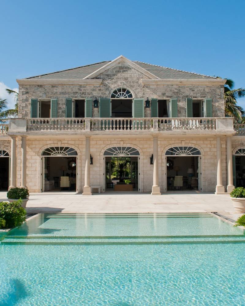 Lounge by the turquoise waters of this luxurious villa's infinity pool, surrounded by lush palm trees and elegant architecture.