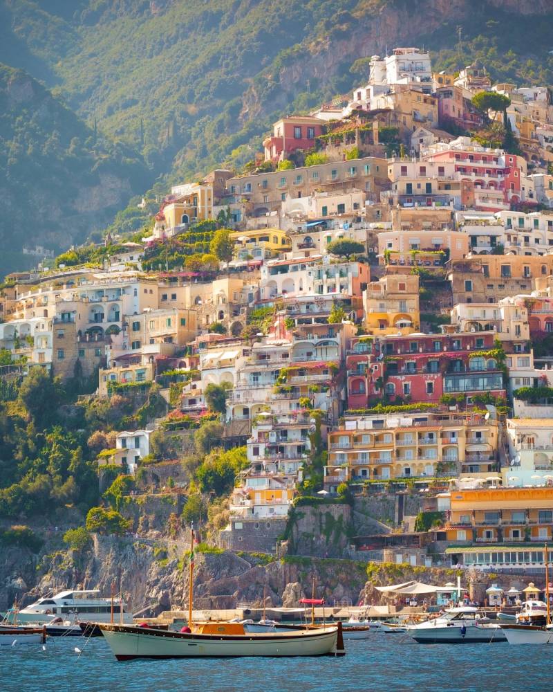 Colorful buildings cascade down a steep hillside to the sparkling blue waters of the Amalfi Coast.