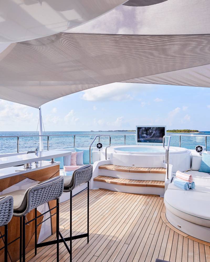 Relax and unwind in the luxurious outdoor lounge area of this yacht, complete with a bar, jacuzzi, and stunning ocean views.