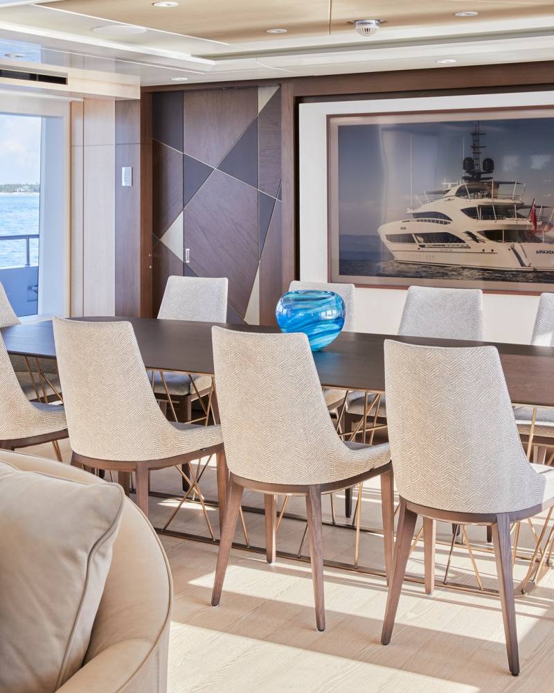 A sophisticated dining room aboard a yacht offers stunning ocean views complemented by modern art and elegant seating.