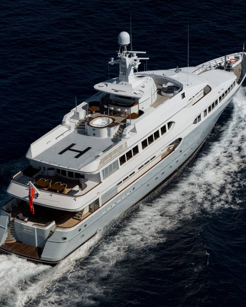 A luxurious yacht cruises through the deep blue ocean, leaving a frothy white wake behind it.