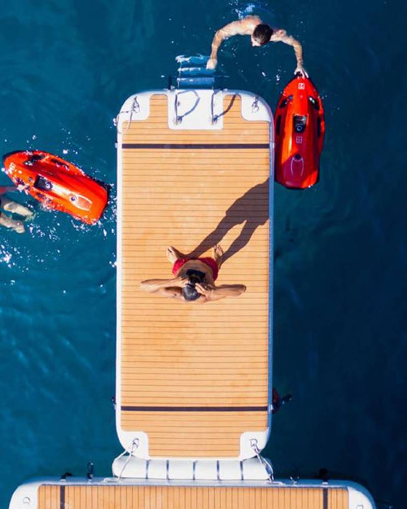 People enjoy a sunny day on the water with inflatable toys and a floating dock.