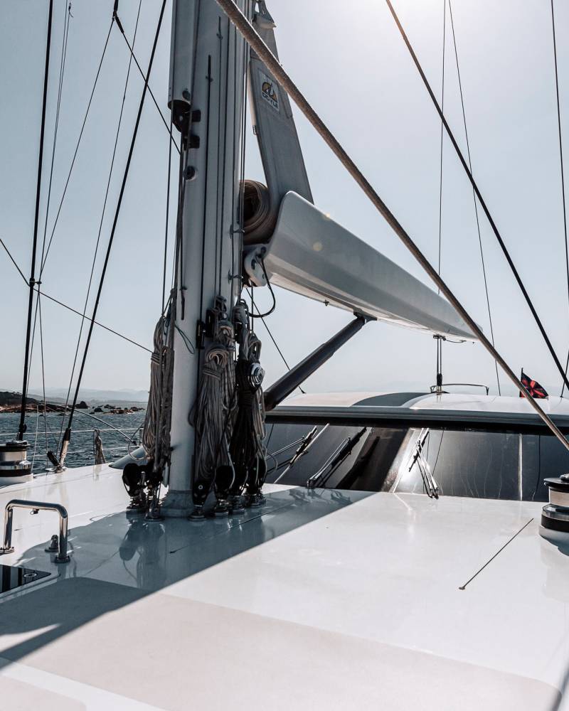 Sailing across the sparkling blue sea, the yacht's deck offers a pristine view of the sun-drenched coastline.