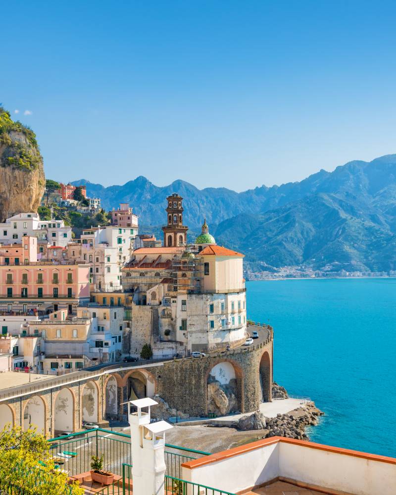 Bright yellow lemons hang in the foreground of a stunning Italian coastal town with colorful buildings cascading down a cliffside.