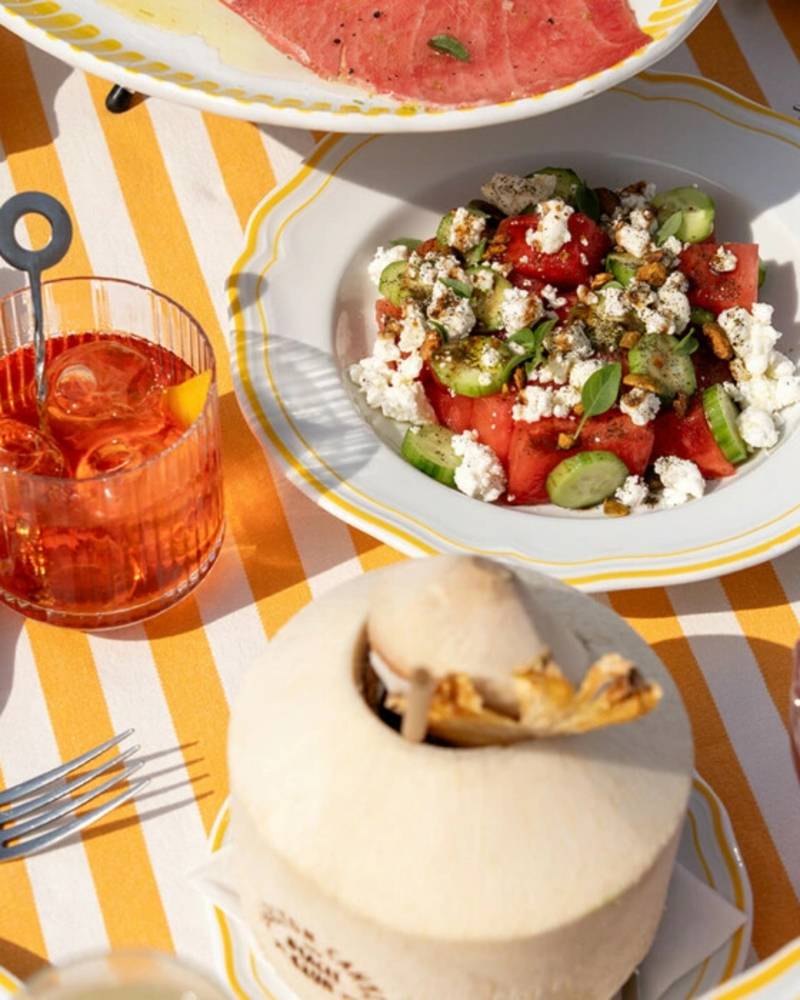 A refreshing spread of watermelon salad and cocktails awaits on a sunny table at the Carlton Beach Club in Cannes.