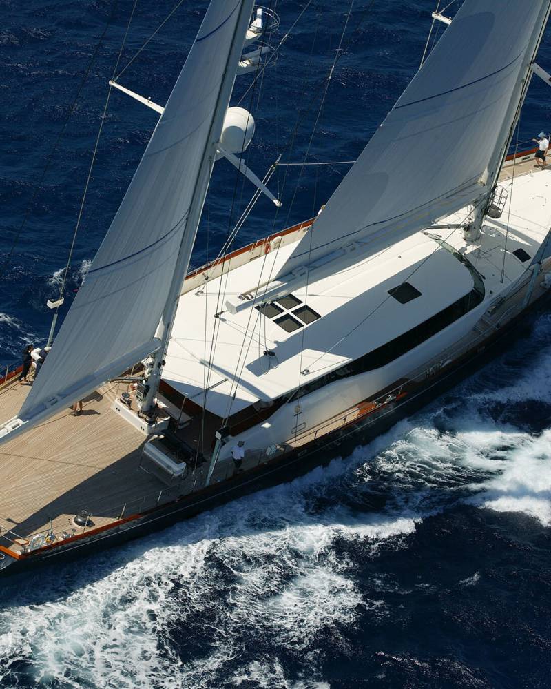 A majestic sailing yacht glides through the deep blue ocean, its sails billowing in the wind.