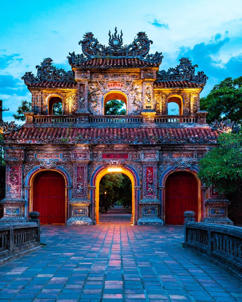 The ornate Ngo Mon Gate in Hue, Vietnam, glows under the twilight sky, inviting visitors into the Imperial City.