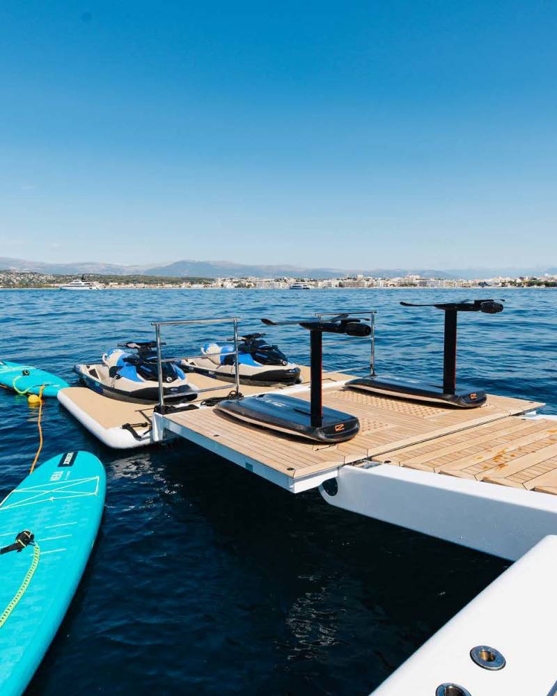 A collection of personal watercraft and electric hydrofoil boards await adventure on a sunny day at sea.