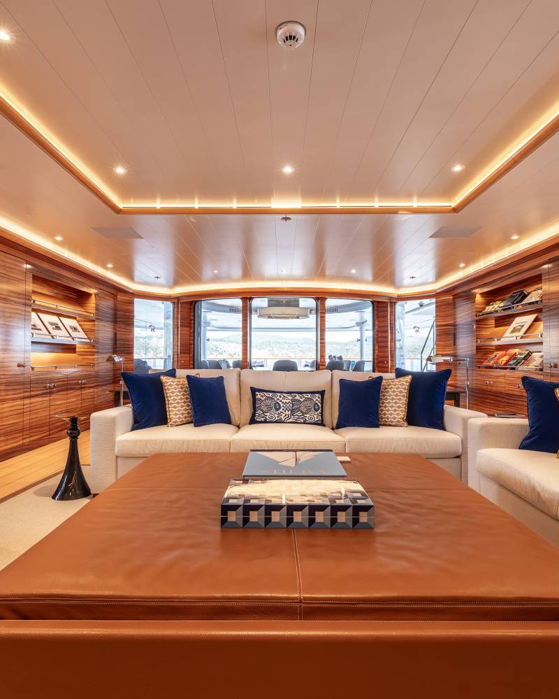 Luxurious yacht salon features warm wood paneling, comfortable seating, and panoramic views of the sea.