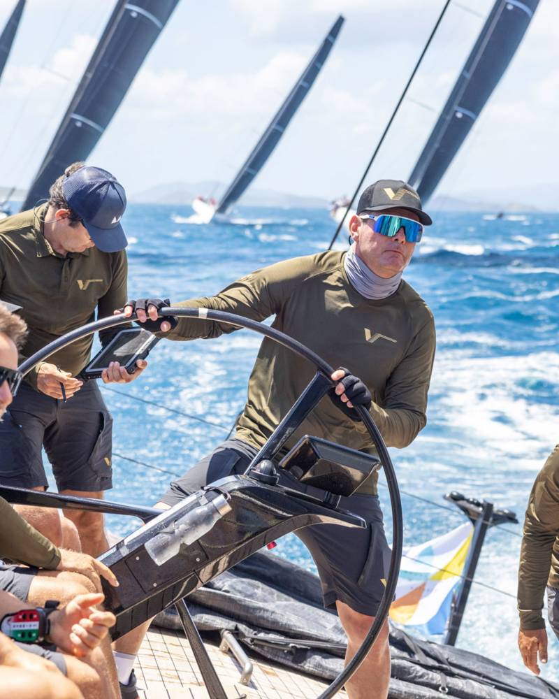 Sailors navigate choppy blue waters under a bright sky as they compete in a regatta.