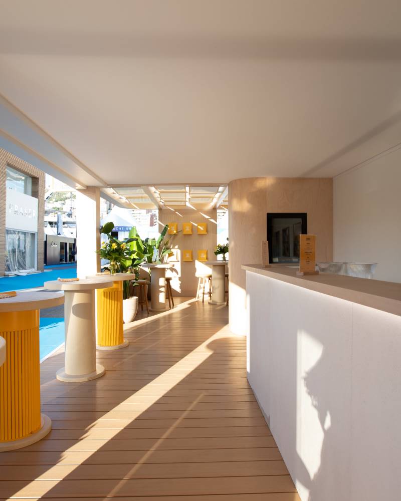 Sunlight streams across a modern outdoor lounge area featuring yellow accents and sleek furniture.