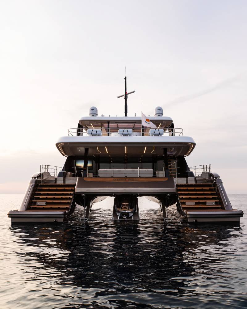 This luxurious catamaran yacht, docked at sea, features a sleek design with multiple levels and a jet ski ready for adventure.