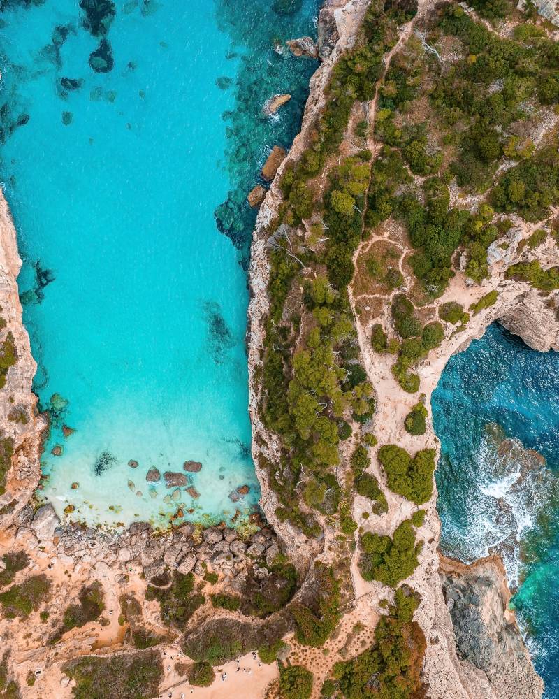 Stunning turquoise waters surrounded by rugged, rocky cliffs and lush, verdant vegetation, creating a breathtaking natural landscape.